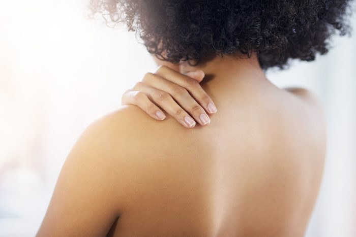 woman rubbing lotion on back