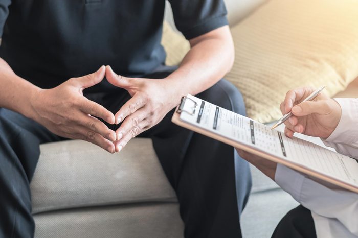 Male patient having consultation with doctor or psychiatrist who working on diagnostic examination on men's health disease or mental illness in medical clinic or hospital mental health service center