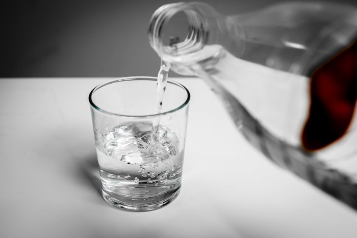 Pouring water into a glass from a bottle. The glass is filled with water.