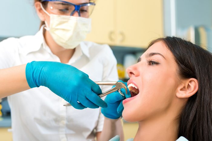 dentist pulling woman's tooth out