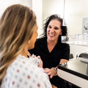 Nurse Preparing Female Patient For Mammogram In Doctor's Office