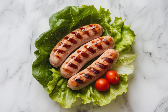 A photo of grilled sausages on lettuce leaves