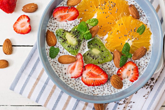 Detox and healthy superfoods breakfast in bowl. Vegan almond milk chia seeds pudding with strawberries, orange and kiwi. Top view. Flat lay
